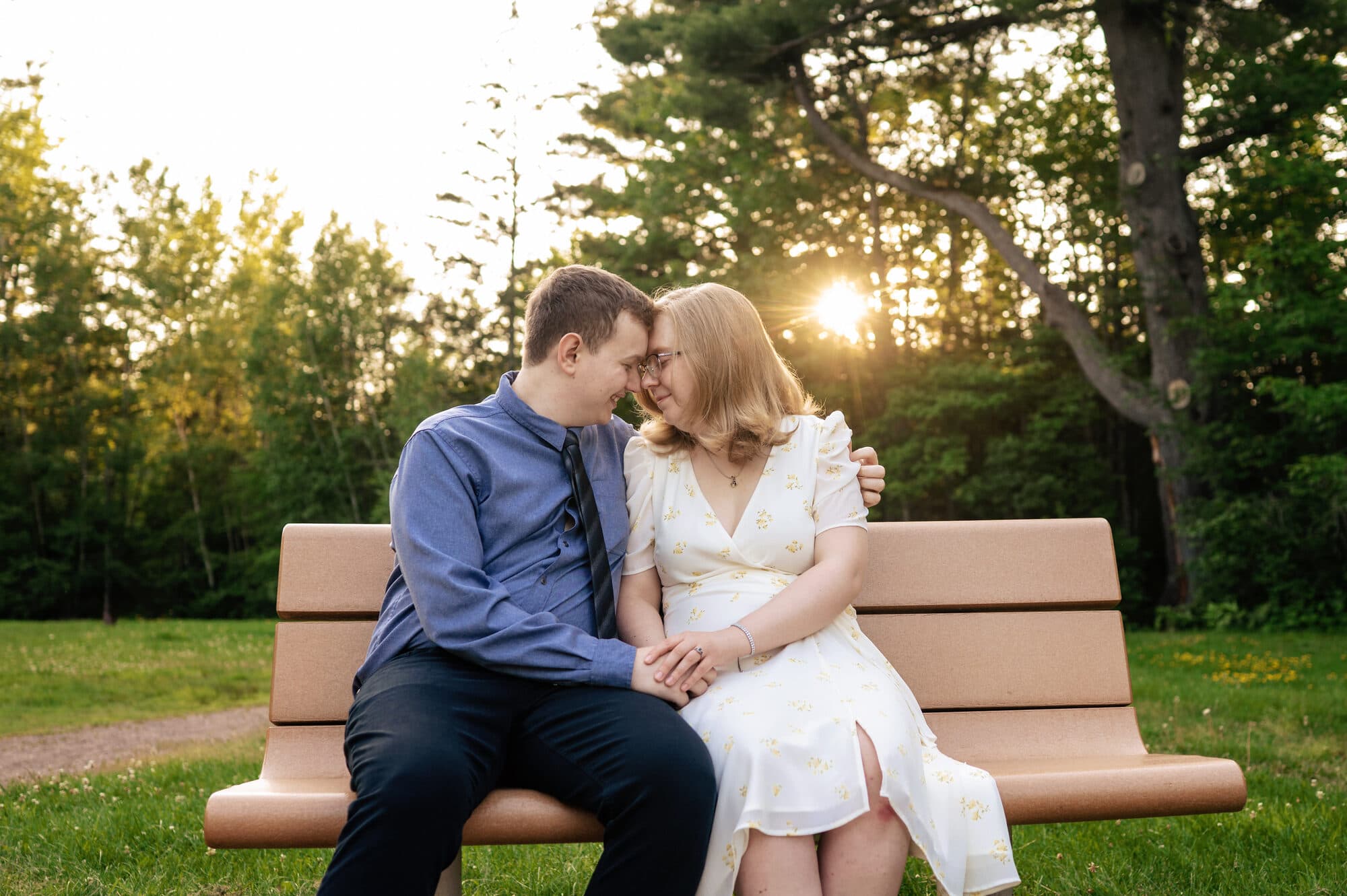 Alexandra and Jérémy sitting close on a park bench at sunset